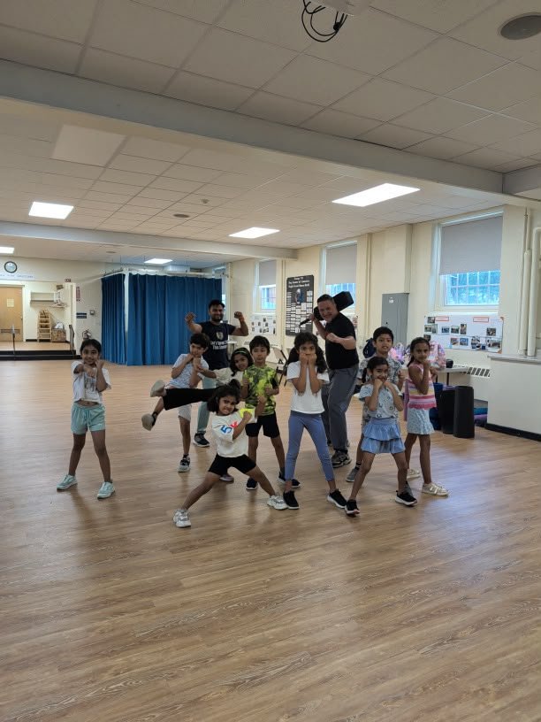 Kids in martial arts self-defense poses with instructor